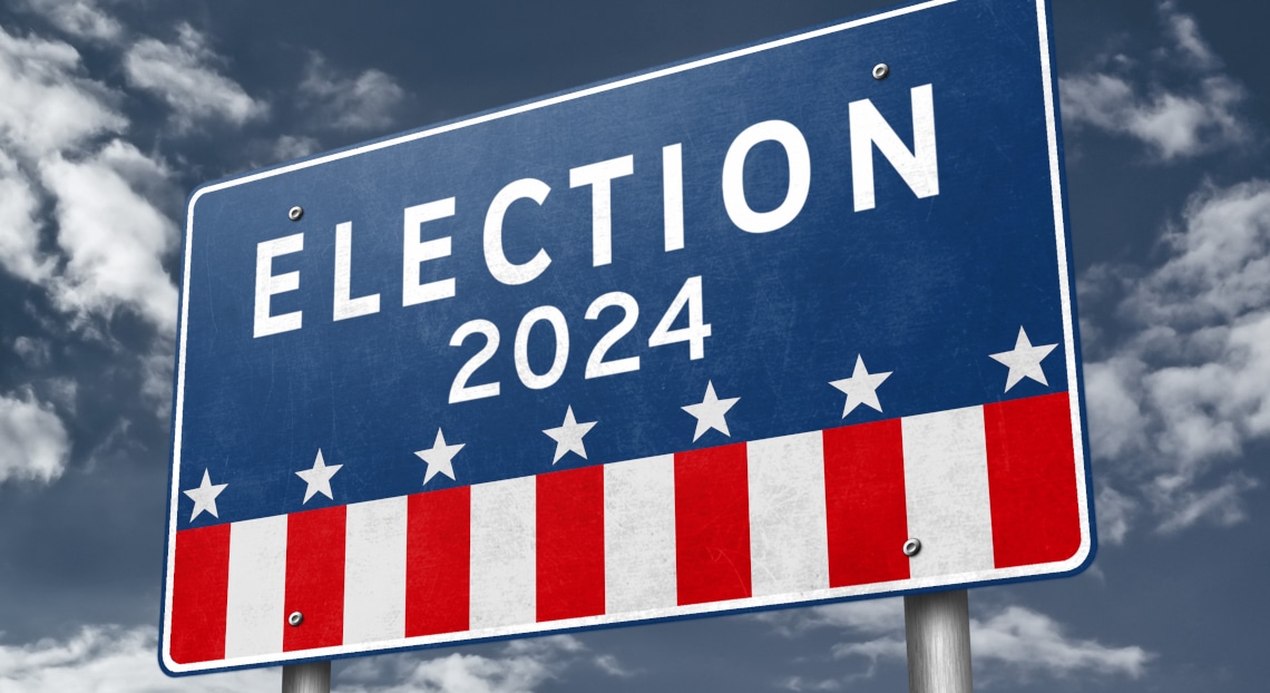 Sign with stars and stripes reads "Election 2024" against clouds.