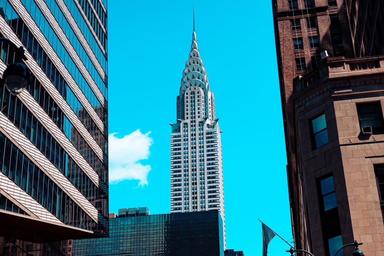 Chrysler Building framed by skyscrapers against clear blue sky.