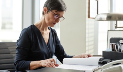 Side view portrait of elegant mature woman as female boss working with reviewing lease at desk.