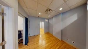 Room with blue walls, wooden floor, in Suite #405, 928 Broadway.