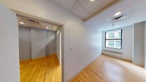 Bright room with wood floor, white walls, and large window at 928 Broadway #405