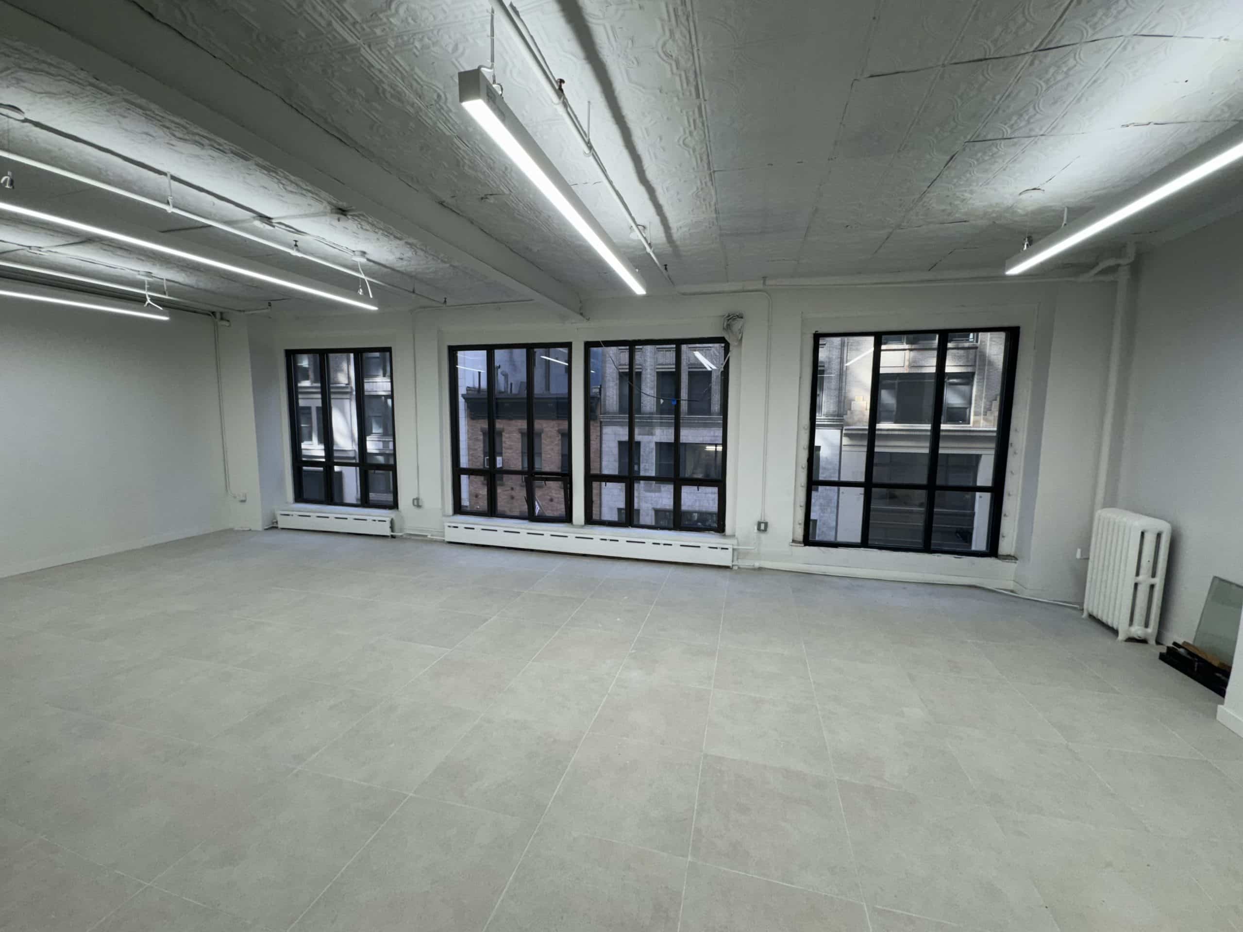 Spacious room, gray floor, white walls, large windows; modern vibe.