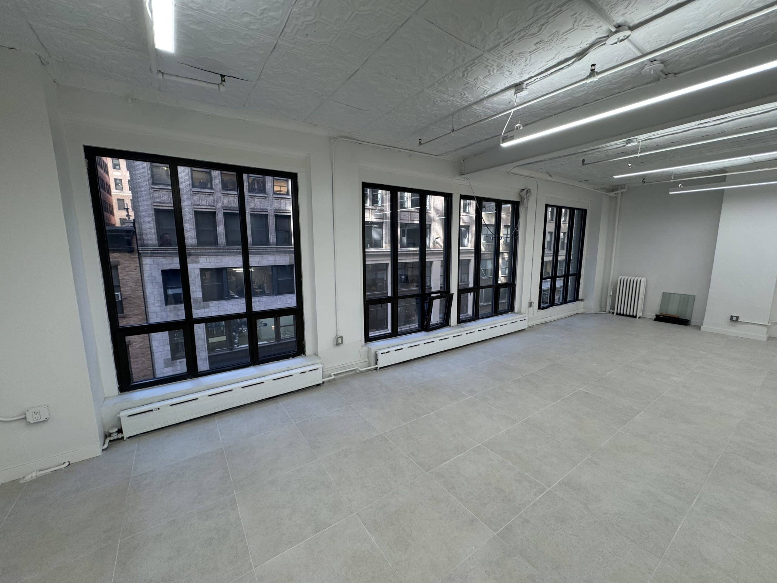 Spacious, empty room with large windows and natural light.