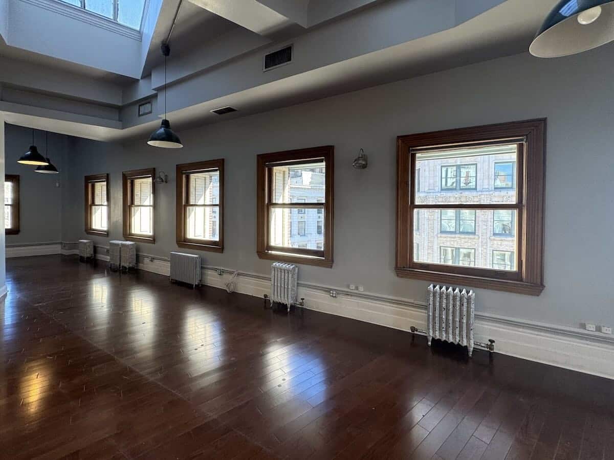 Spacious room with large windows, dark floors, and pendant lights.