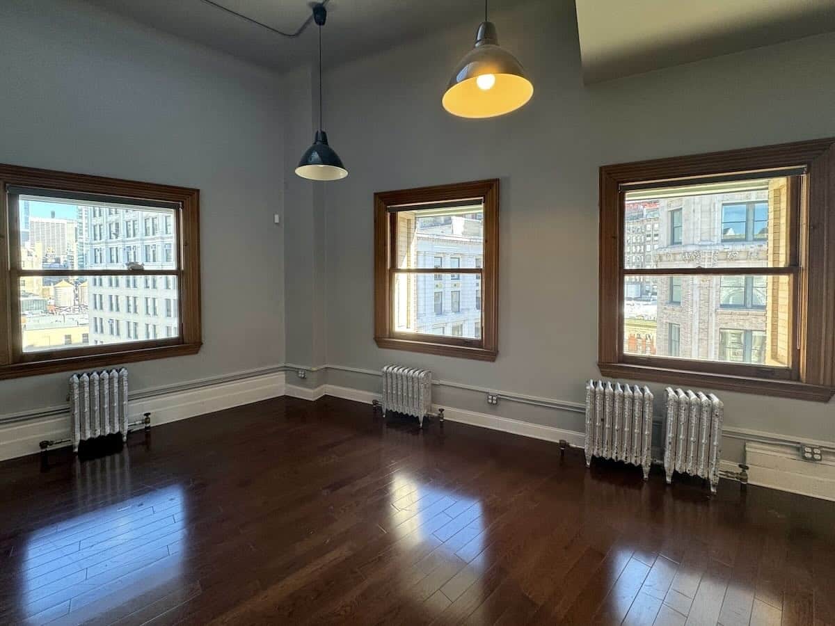 Room #1615 with wooden floors, large windows, and gray walls.