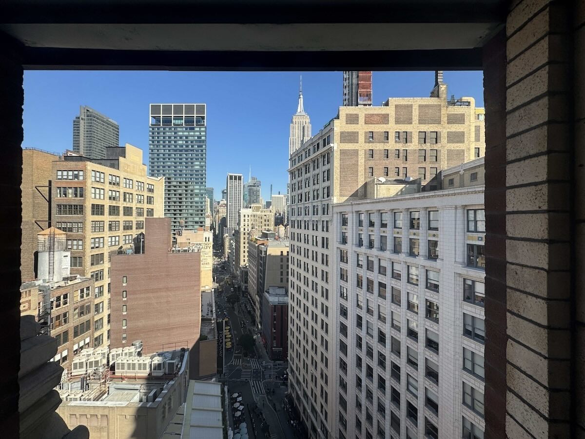 Cityscape with tall buildings and 1133 Broadway's spire in clear sky.