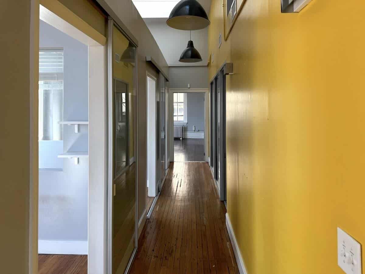 Vibrant hallway at 1133 Broadway with wooden floors and yellow walls.