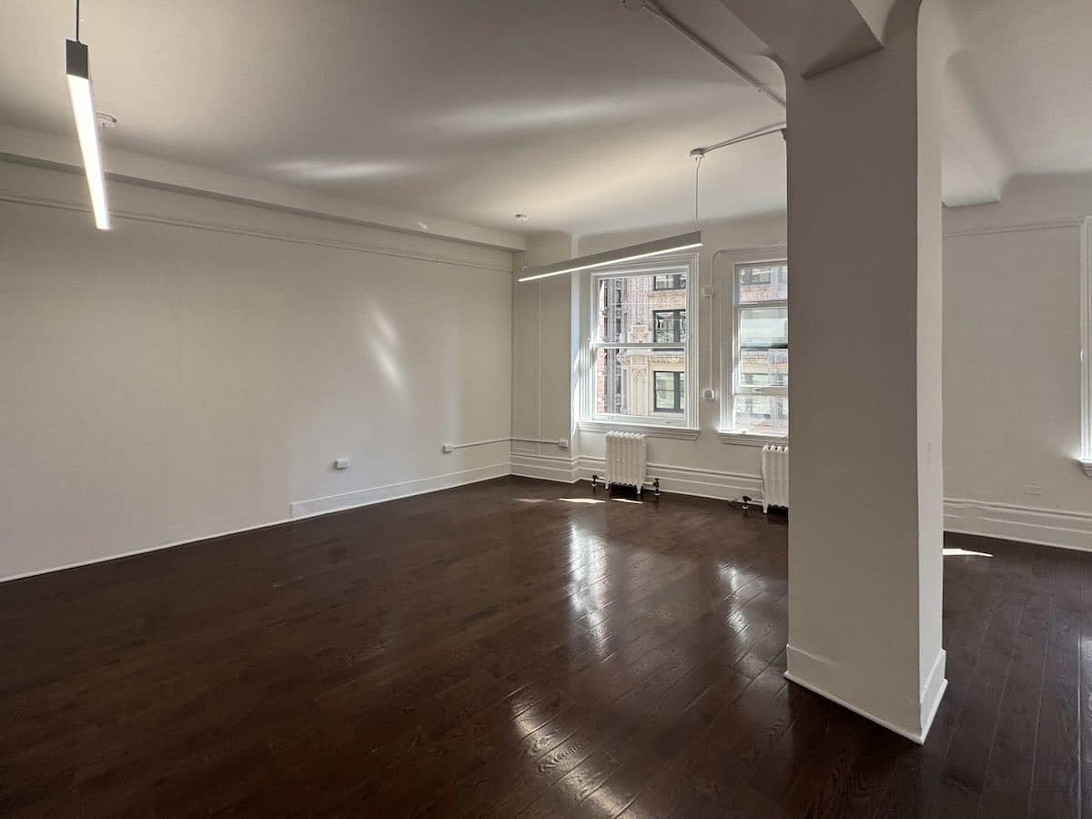 Spacious room with dark floors, white walls, and large windows at1133 Broadway, #630