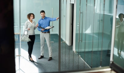 Man giving office tour to woman in sunny, modern space