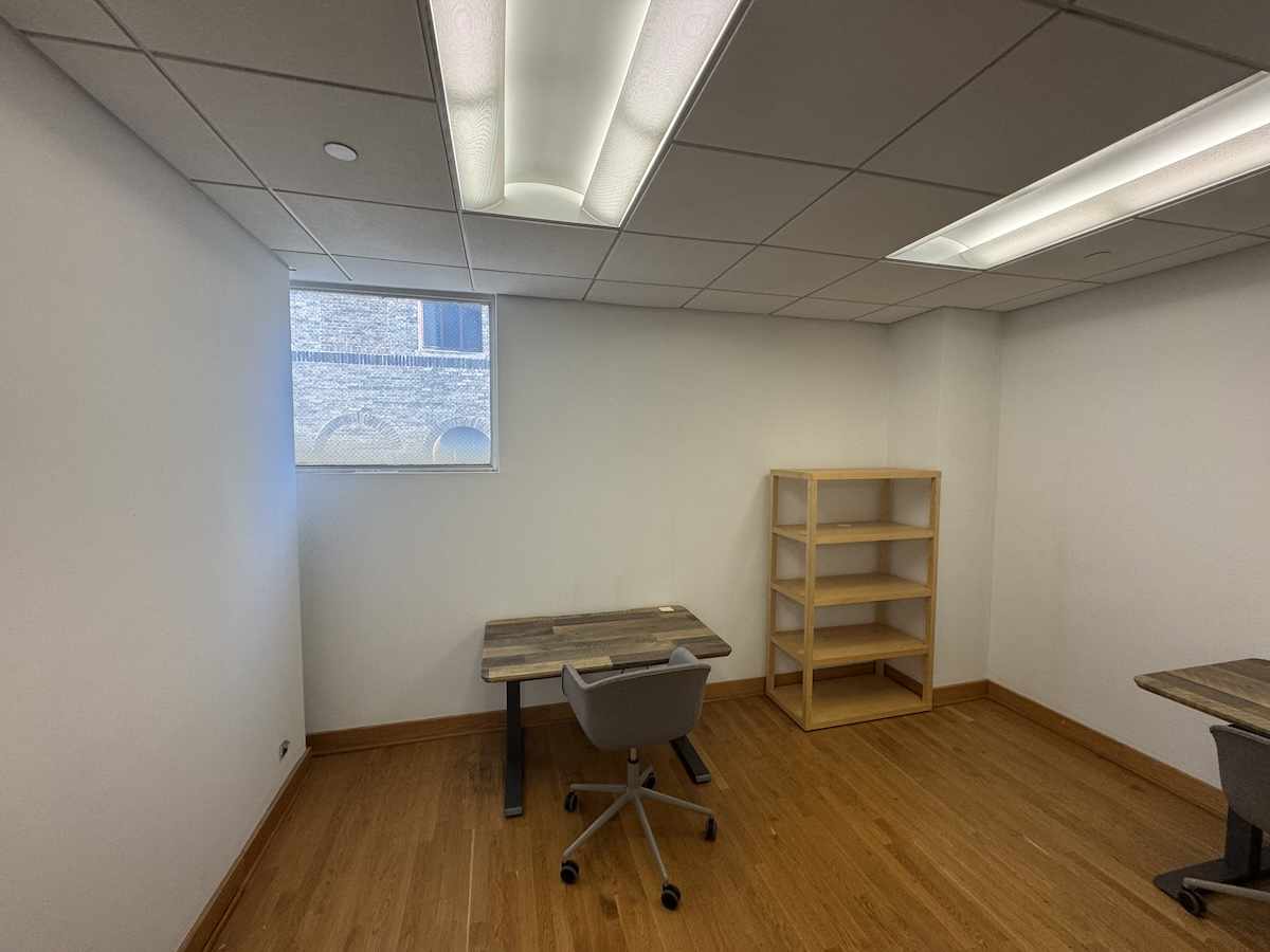 Small office on East 40th St, wood floor, desks, chair, window.