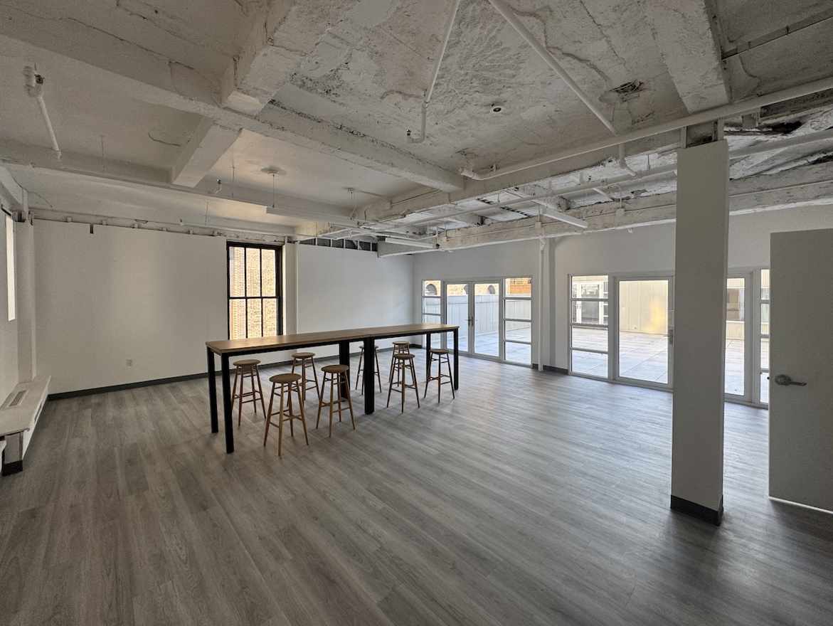 Modern industrial penthouse with beams, large windows, and bar stools.