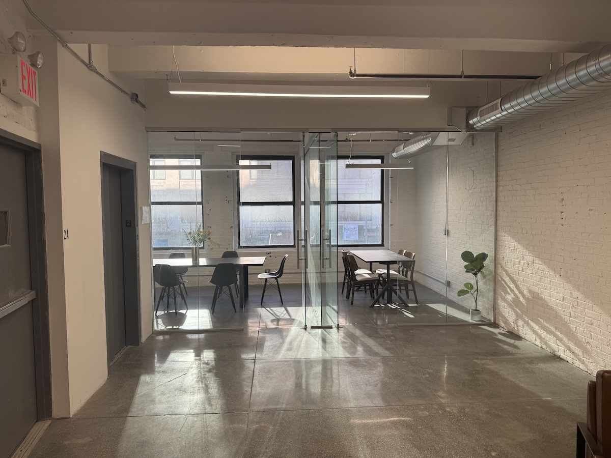 Modern office space with glass-walled meeting room, natural light.