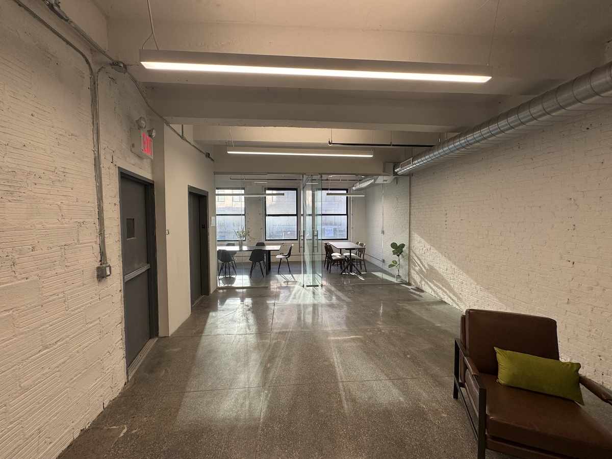 Modern office: concrete floors, white brick walls, cozy seating.