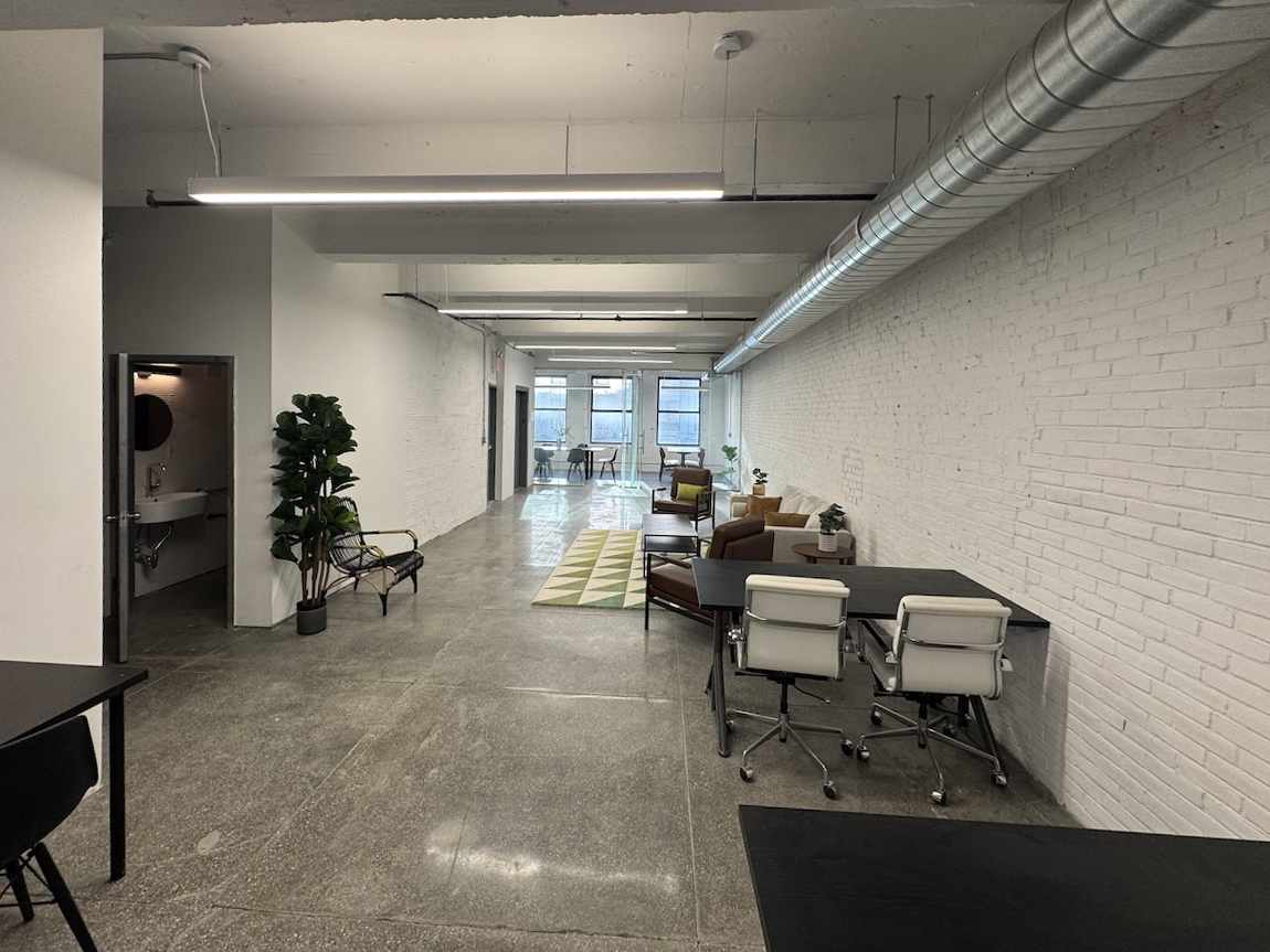 Modern office space with white walls, concrete floors, and large windows.