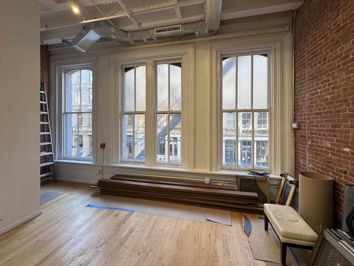 Renovated room with large windows, exposed brick, and sunlight.