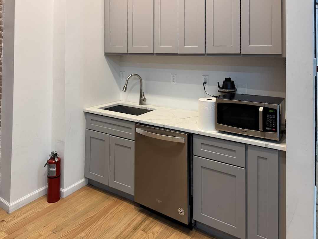 Modern kitchen with grey cabinets, white countertop, and dishwasher.