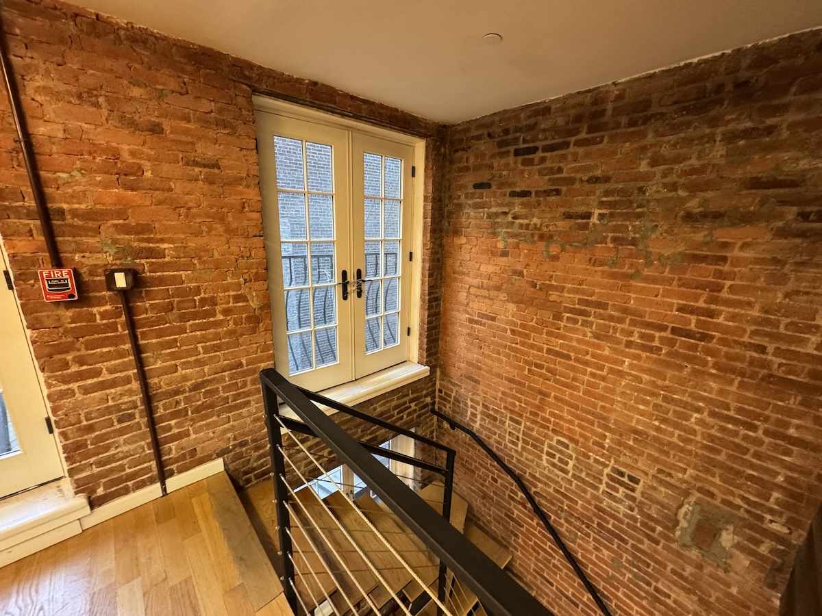 Wooden steps with metal railing and brick walls at 460 Broome St.