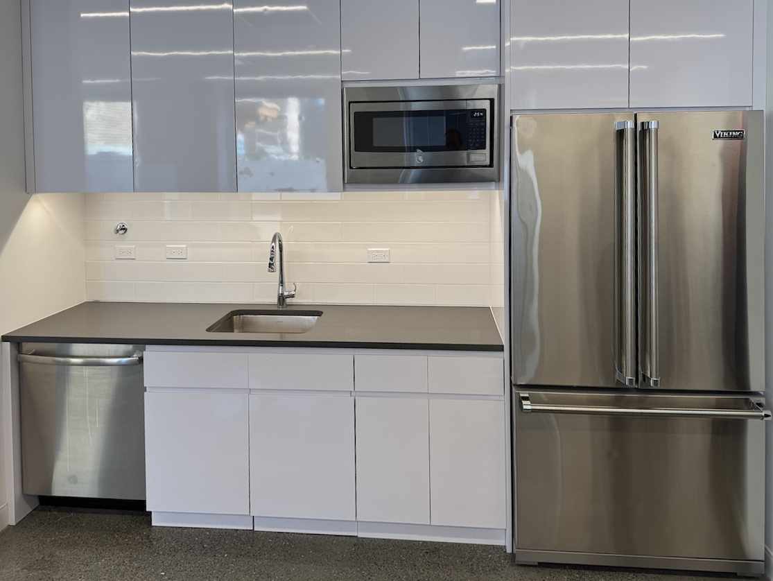 Modern kitchen with white cabinets and stainless appliances.