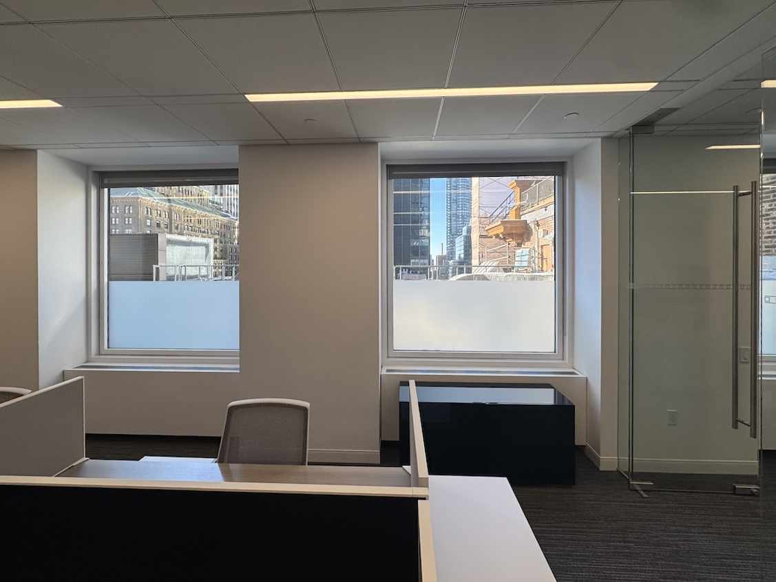 Modern office with desk, chair, and cityscape views through windows.