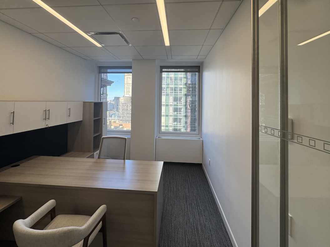 Suite 16N: cozy office with wooden desk, city view, and glass partition.